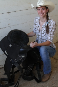 Bethany Peterson picks up her saddle in preparation for a trail ride.